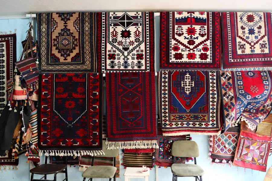 Duvarda sıralı Yağcıbedir halıları, lacivert kırmızı ve beyaz motifler