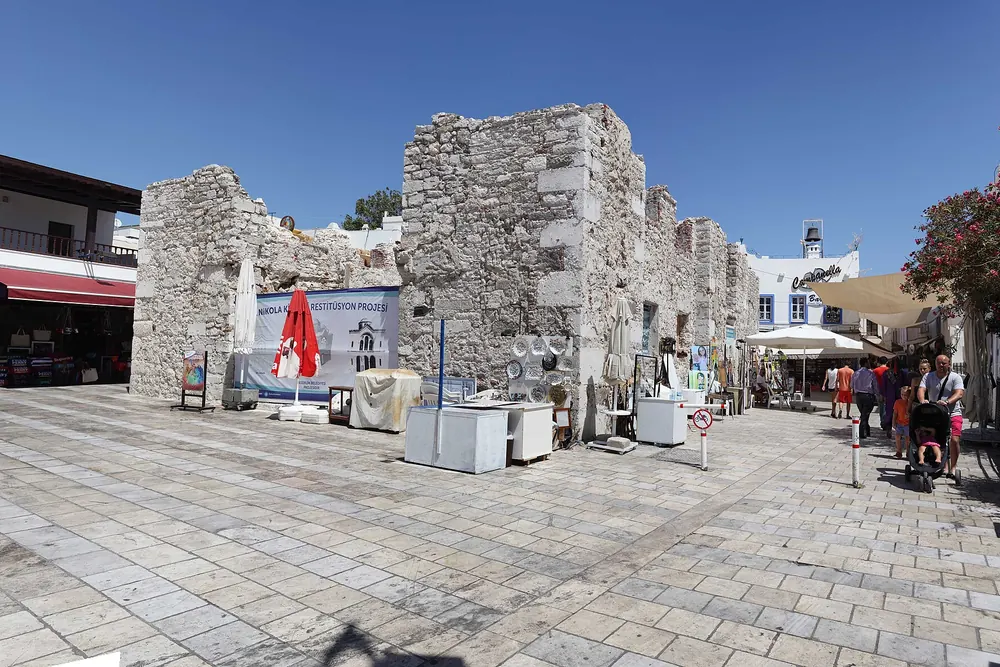 Bodrum çarşısında taş döşeli bir yaya meydanı, açık hava kafe masaları