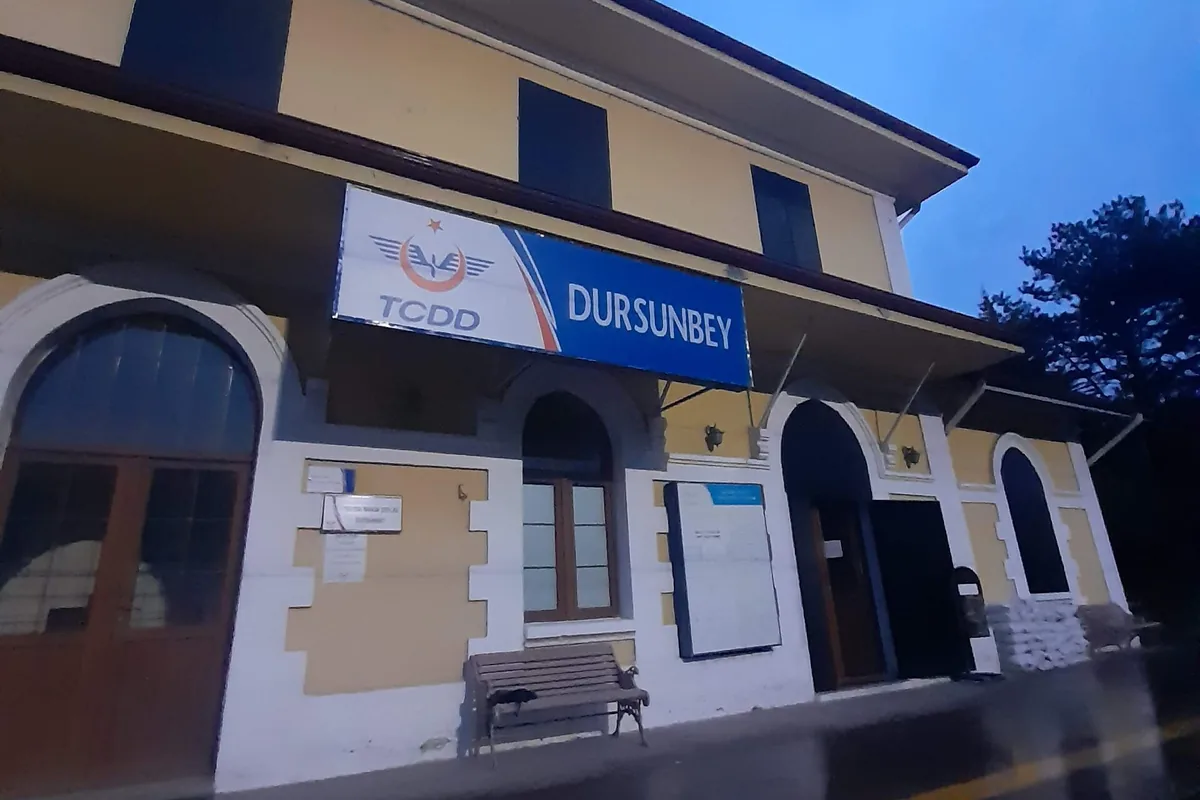 Dursunbey TCDD tren garının akşam ışığında sarı taş cephesi ve 'DURSUNBEY' tabelası