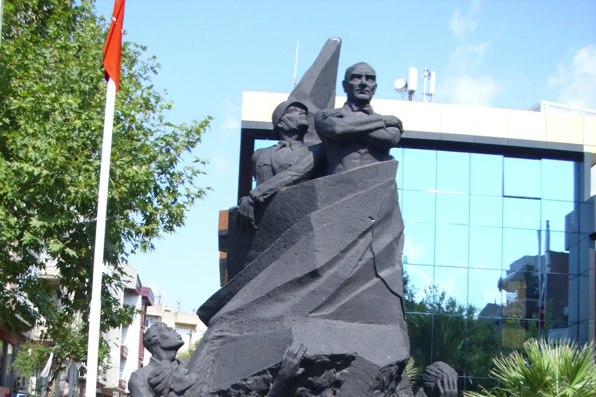 Erdek merkezindeki Atatürk Anıtı heykel grubu, arka planda modern bir bina