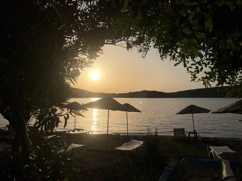Eski Foça sahilinde gün batımı ve hasır şemsiyeler