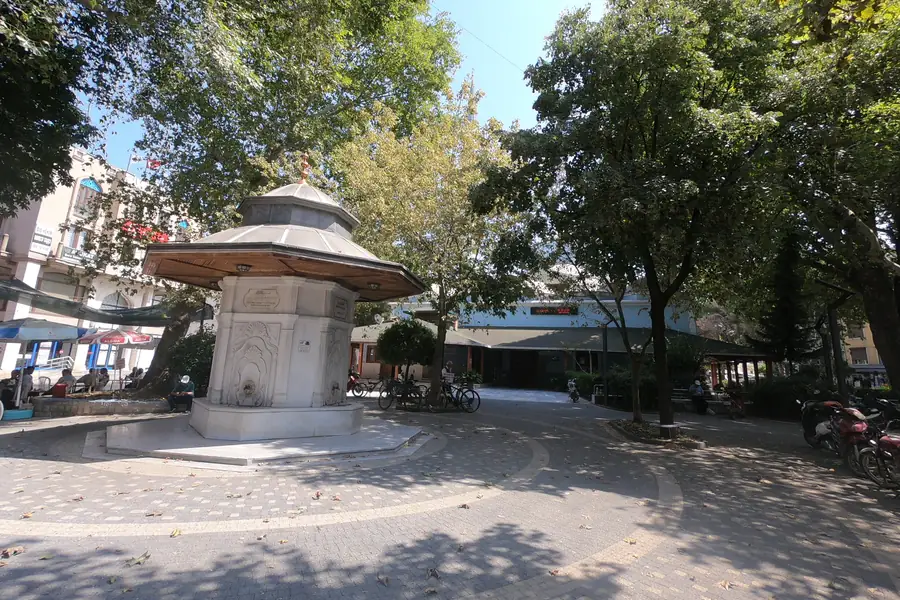 Gönen Çarşı Camii bahçesindeki tarihi taş çeşme (şadırvan), etrafında ağaçlar ve meydan