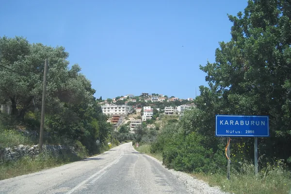 Karaburun girişindeki yol tabelası ve arkasında kasaba