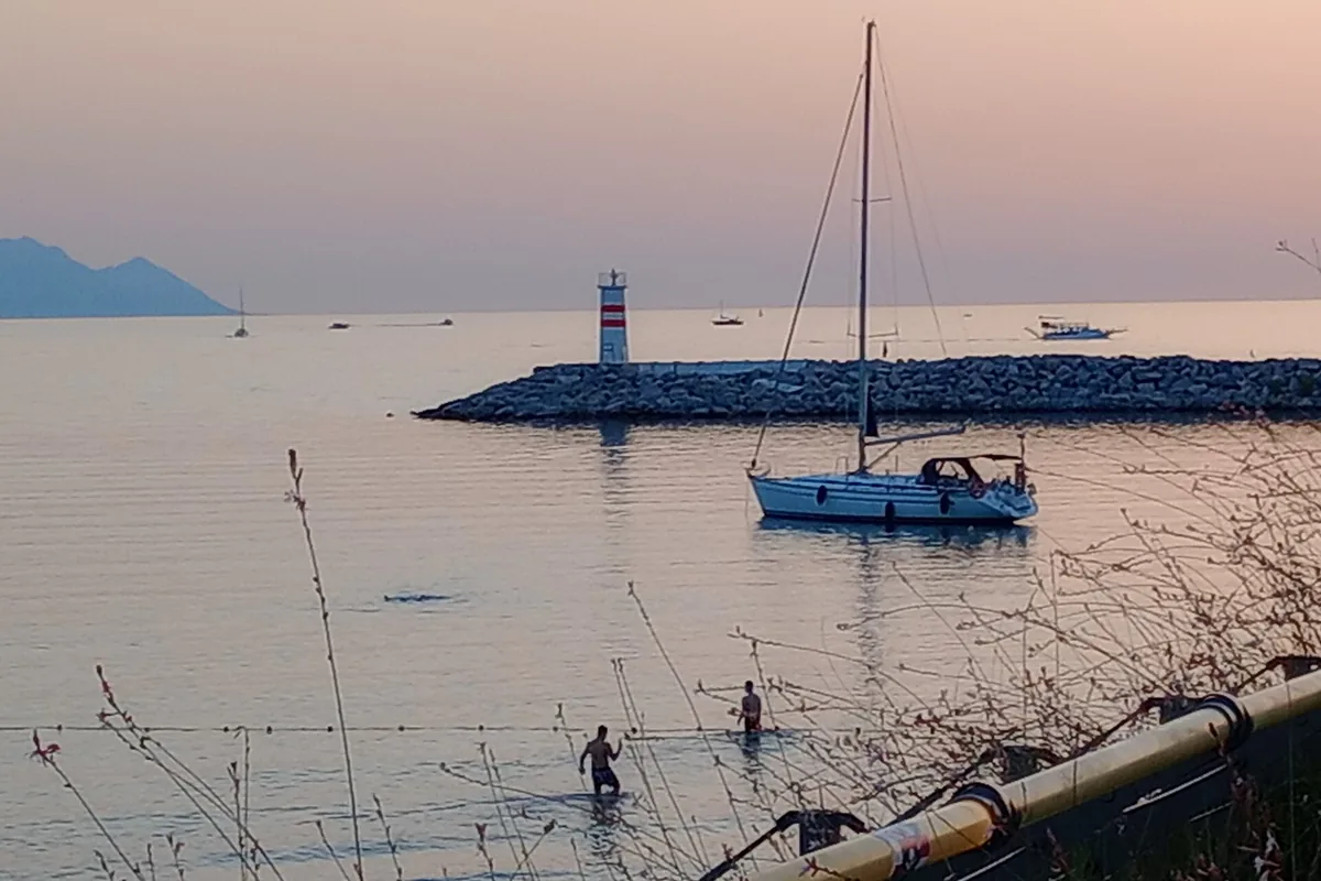 Kuşadası plajında deniz feneri ve demirlemiş yelkenli