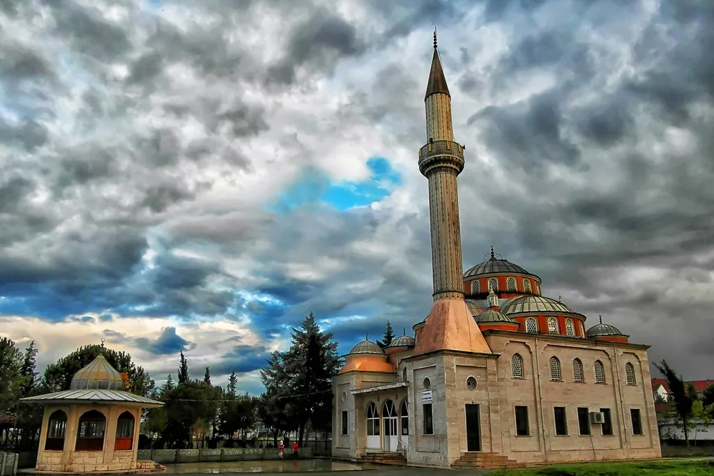 Manyas İmam Hatip Camii'nin minaresi ve kubbeleri, dramatik bulutlu gökyüzü altında